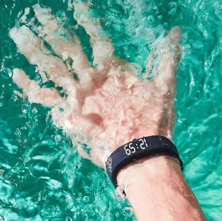 Person's hand wearing a Polaristech Smart bracelet in water, displaying time, a stylish bracelet for health tracking.