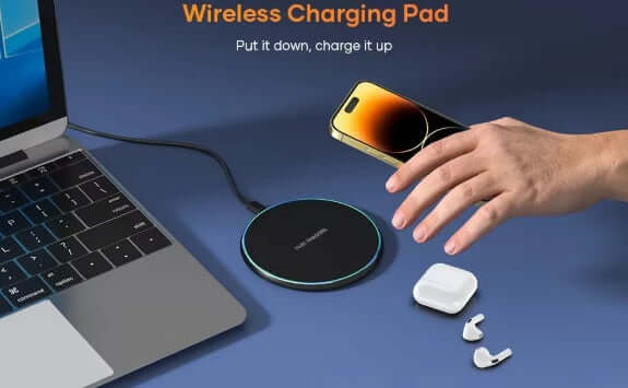 Charger on desk with smartphone and earbuds on a wireless charging pad, demonstrating convenience of wireless charging.